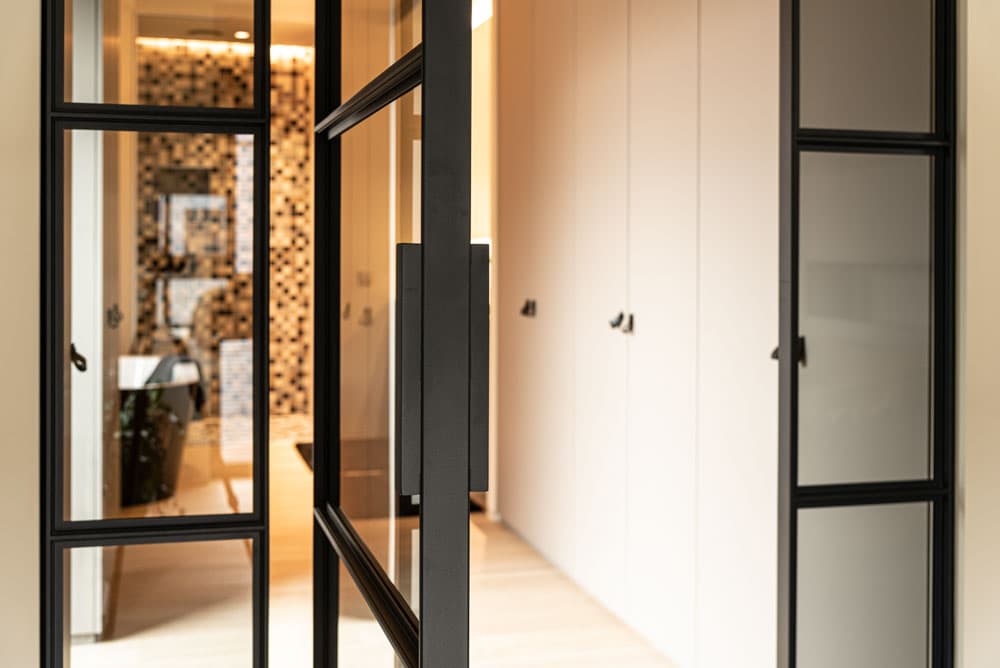 a single pivot door made of steel in a black finish and clear glazing